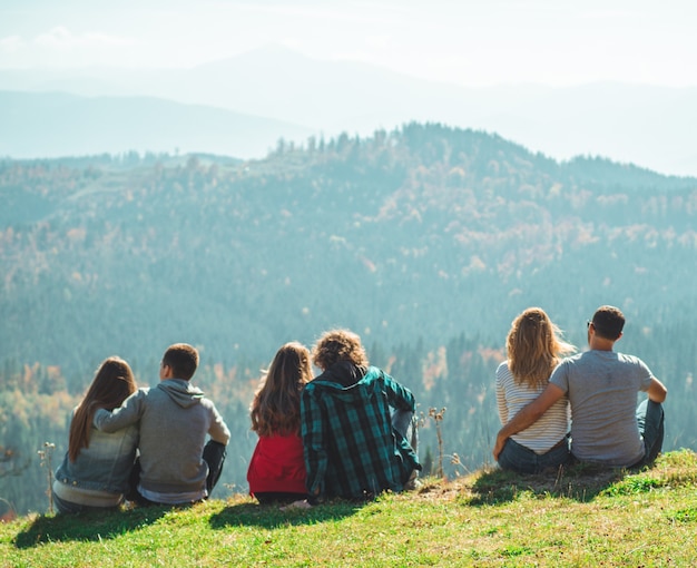 Einige Paar Reisende Jungen und Mädchen sitzen auf Klippe entspannende Berge und Wolken Luftbild Liebe und Reisen glückliche Gefühle Lifestyle-Konzept.