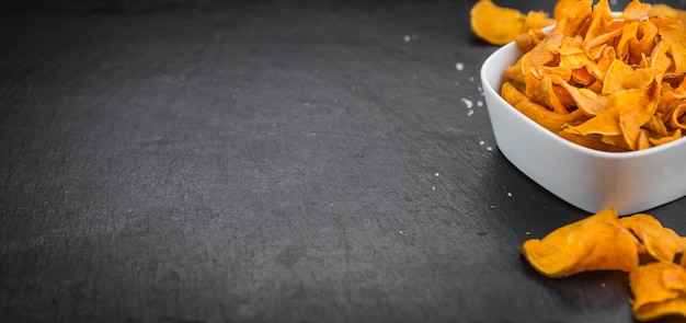 Einige Süßkartoffelchips auf einer dunklen Schieferplatte