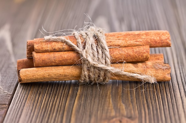 Einige Zimtstangen, die mit Schnur auf einem alten Holzbrett gebunden sind