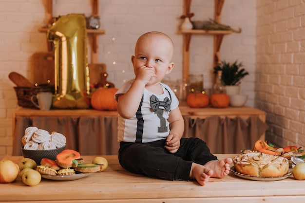 Einjähriges Baby isst hausgemachten bemalten Lebkuchen. ersten Geburtstag in festlicher Atmosphäre. Gesunder Snack für Kinder. kleiner Junge sitzt am Küchentisch. Foto in hoher Qualität