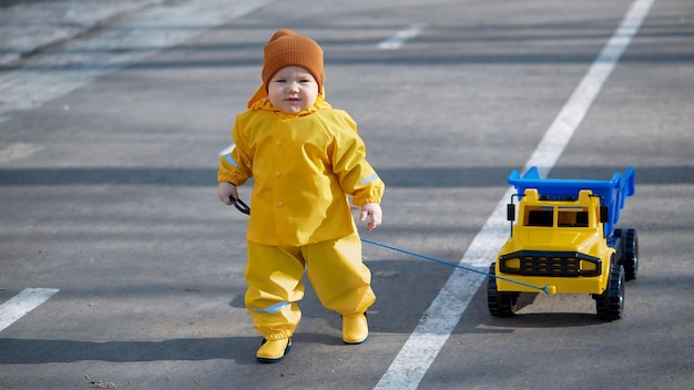 Einjähriges Kind rollt einen Spielzeuglastwagen die Straße entlang