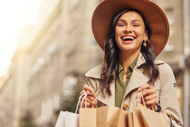 Einkaufen als Therapieporträt einer jungen aufgeregten Frau mit grauem Mantel und Hut