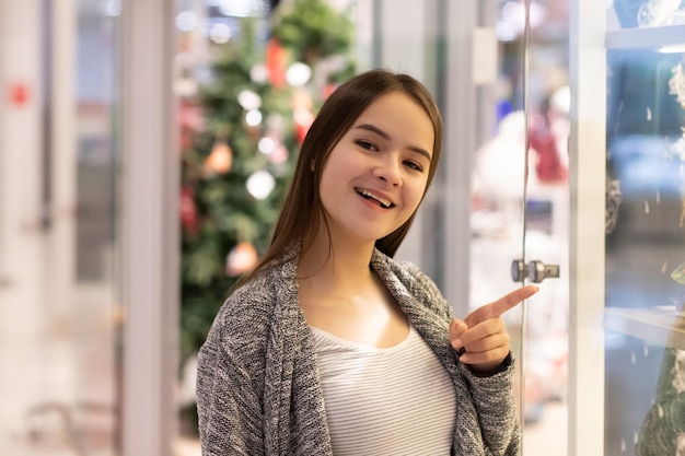 Einkaufen Ein junges Mädchen zeigt in einem Einkaufszentrum auf ein Schaufenster, hat das richtige Produkt gefunden.