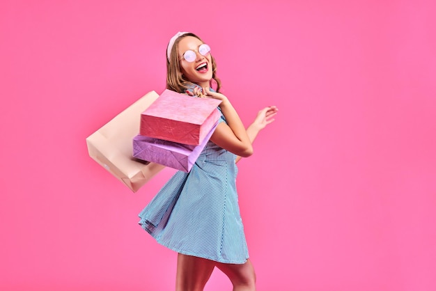 Einkaufen Frau glücklich lächelnd mit Einkaufstüten isoliert auf rosa Hintergrund Kopieren Sie Platz