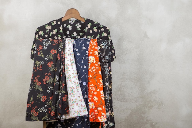 Einkaufs- und Stilkonzept Kleiderständer mit trendigen Kleidern im Blumendruck auf Holzboden