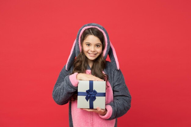 Einkaufsgeschenk für Feiertage, Weihnachten oder Neujahr, süßes Kind im flauschigen Kaninchenpyjama, Geschenkbox halten, fröhliches Kind, Geburtstag feiern, Teenager-Mädchen, genießen, Boxtag, glückliche Kindheit. Es ist ein Schnäppchen