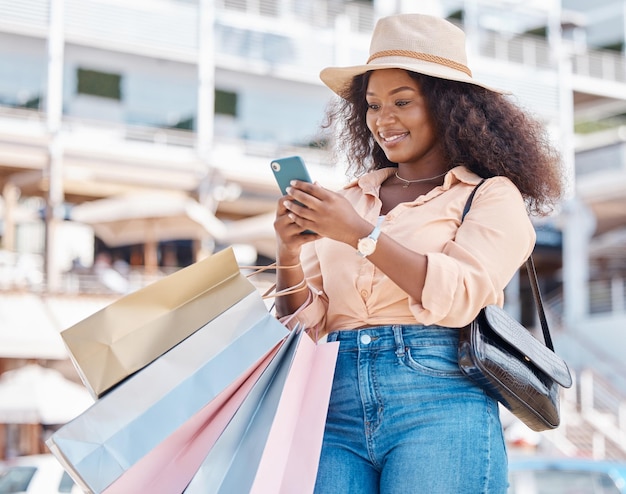 Einkaufstasche für den Einzelhandel mit schwarzen Frauen und Smartphone-Suche in der Stadt Modeverkäufe soziale Medien und Online-Newsletter Rabattcode und Ladenaktionen Wohlhabender Kunde, der das Telefon über die mobile E-Commerce-App verwendet