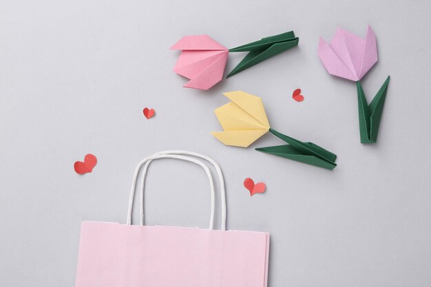 Einkaufstasche und Herzen Tulpen auf grauem Hintergrund Weihnachtseinkäufe Rabatte Verkauf Valentinstag Zusammensetzung
