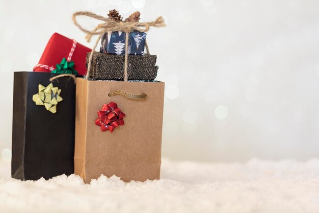 Foto einkaufstaschen mit verpackten weihnachtsgeschenken im inneren auf schnee mit verschwommenem hintergrund mit kopierraum