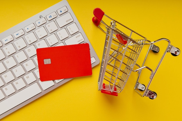 Einkaufswagen und rote Kreditkarte auf einer Tastaturnahaufnahme