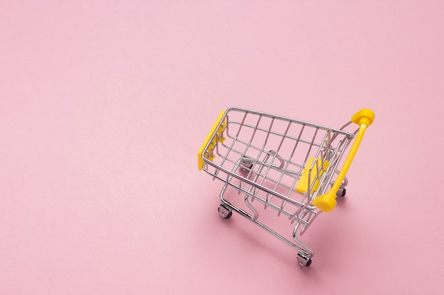 Einkaufswagen vom Supermarkt auf einem isolierten rosa Hintergrund. Einkaufen in der Mall, einkaufen, einkaufen.