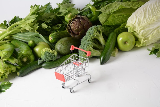 Einkaufswagenwagen und verschiedenes frisches Obst und Gemüse für das Layout Sortiment an frischem Obst und Gemüse Hintergrund für gesunde Lebensmittel Einkaufen von Lebensmitteln im Supermarkt