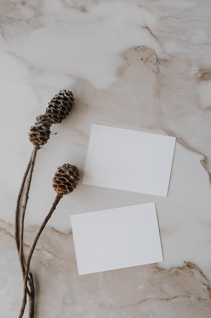 Einladungskarten aus leerem Papier mit Kopierbereich auf neutralem Marmortischhintergrund Flache Ansicht von oben ästhetische minimalistische Hochzeitseinladungen