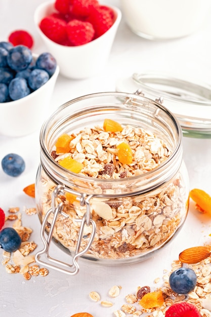 Einmachglas mit hausgemachtem Müsli oder Haferflockenmüsli mit Nüssen, getrockneten Früchten und frischen Beeren.