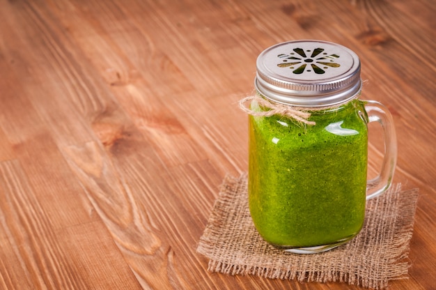 Einmachglasbecher gefüllt mit grünem Spinat und Grünkohlgesundheits-Smoothie