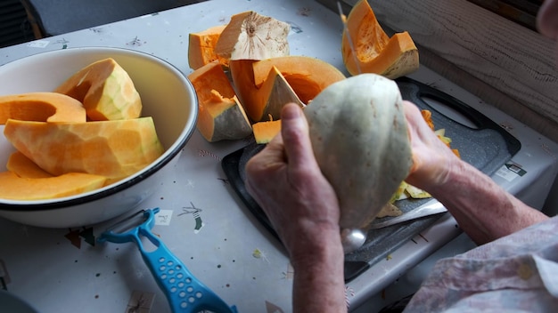 Einsame alte Frau schneidet und Pillen gelber Kürbis, der Kürbissuppe kocht, selektiver Fokus des Ruhestandslebens