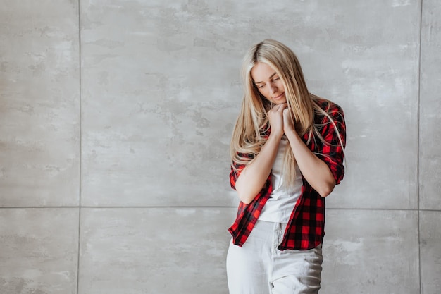 Einsame blonde kaukasische junge Frau im karierten Hemd, die zu Hause in der Frustration Lagainst-Marmor w steht