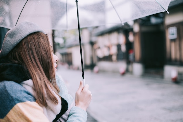 Einsame Frau mit Regenschirm wartet auf den Regen auf der Straße in Japan.