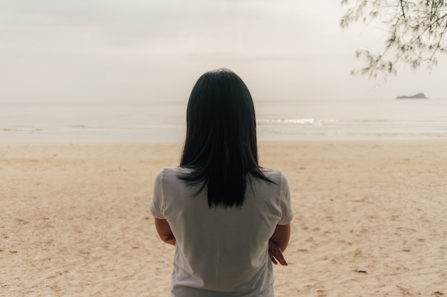 Einsame Frau stehen am Strand und schauen ins Meer.