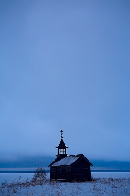 einsame Holzkirche im Feld / Konzept Glaube, Gott, Einsamkeit, Architektur in der Winterlandschaft