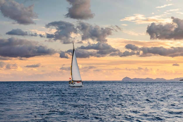 Einsame Yacht mit weißen Segeln im Meer auf einem Hintergrund von schönen Wolken Sommerurlaub