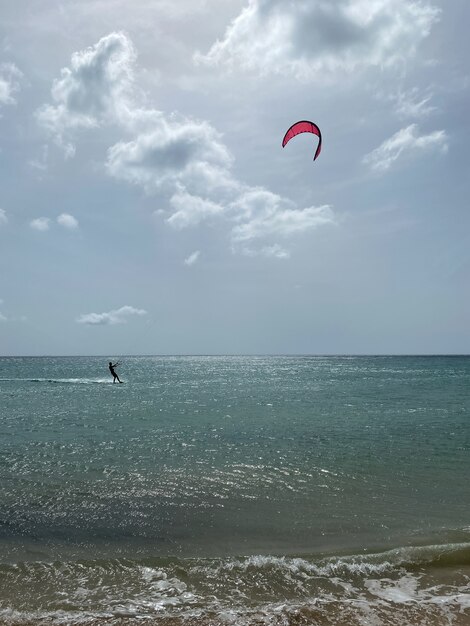Einsamer Kitesurfer, der auf einem blauen Ozeanwasserflugzeug surft