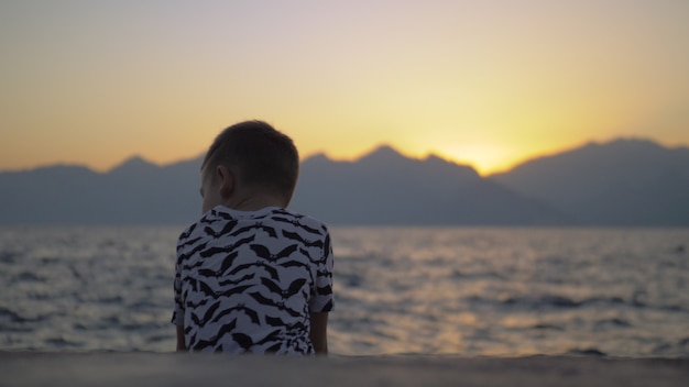 Einsames Kind am Strand bei Sonnenuntergang