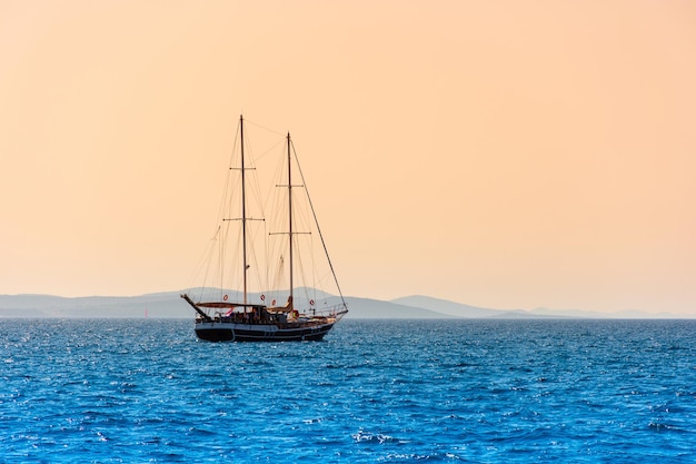 Einsames Segelboot segelt auf dem Meer in der wunderschönen Landschaft der Morgendämmerung