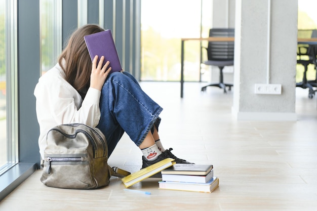 Einsames, trauriges Schulmädchen, während alle ihre Klassenkameraden ihr Problem der sozialen Ausgrenzung, Mobbing in der Schule, ignorierten