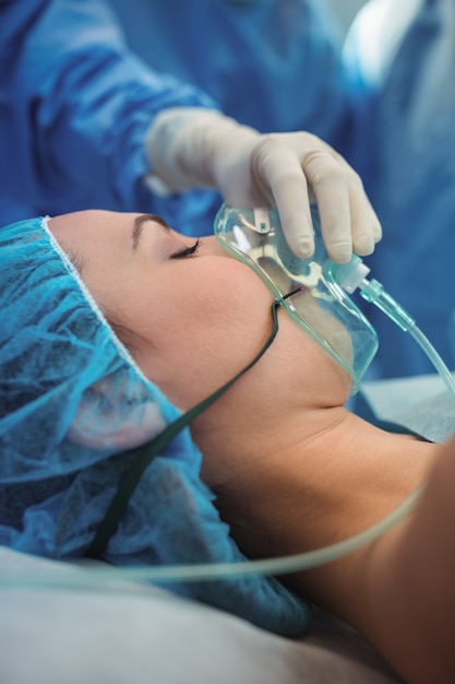 Einstellen der Sauerstoffmaske des Chirurgen am Mund des Patienten im Operationssaal
