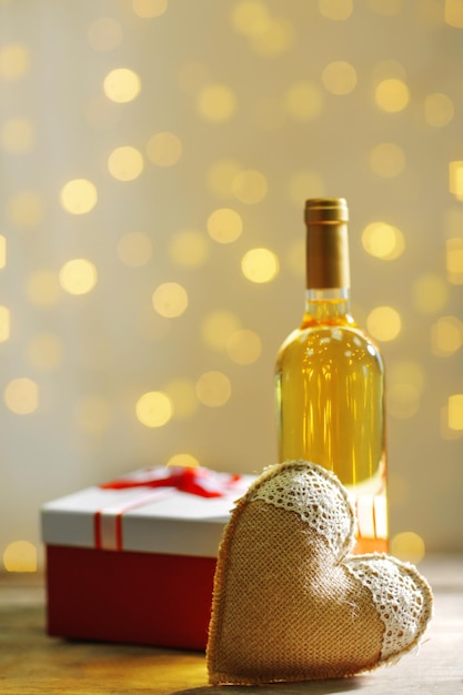 Einstellung einer Flasche Wein, eines Geschenks in der Schachtel und anderer Dekoration auf unscharfem Hintergrund