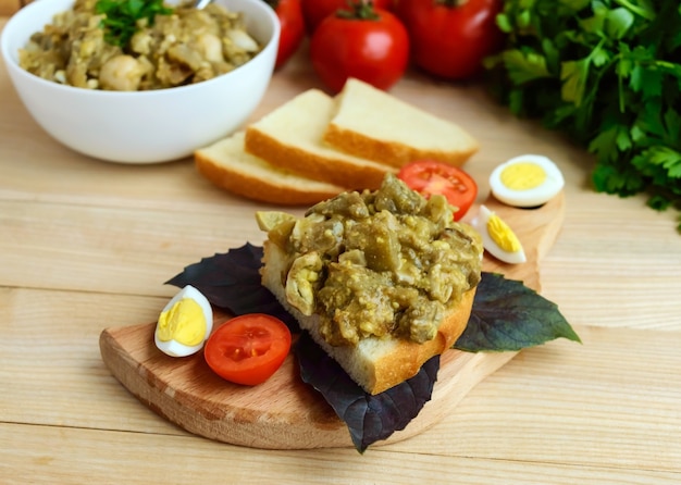 Eintopf aus Auberginen, Wachteleiern und Sahnesauce auf einer Scheibe Weißbrot.