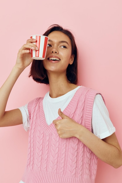 Einweg-Getränkglas des hübschen Mädchens des Fotos in einem rosa T-Shirt rosa Hintergrund