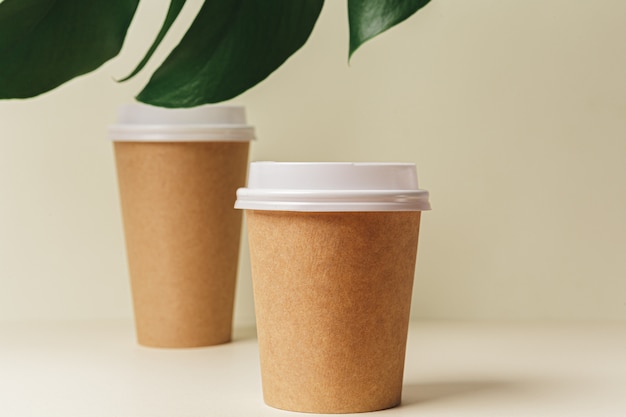 Einweg-Kaffeetasse aus Papier und grünes Blatt. Ökologiekonzept