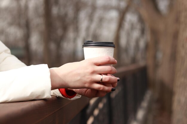 Einweg-Kartonbecher mit Tee oder Kaffee in weiblichen Händen, Nahaufnahme Takeaway-Kaffee