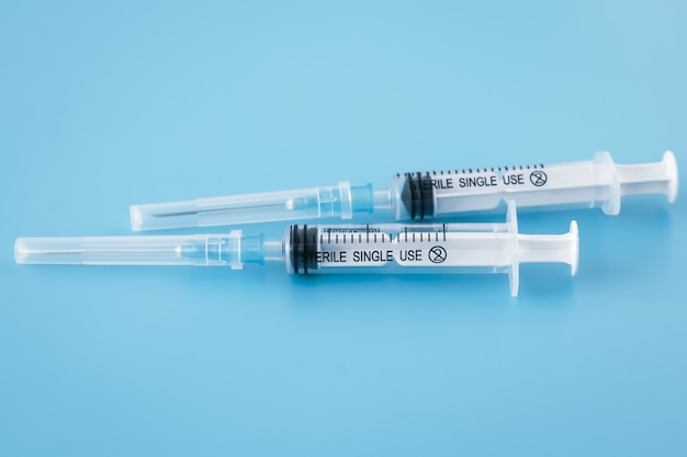 Einweg-Plastikspritze auf blauem Hintergrund. Impfkonzept. Medizinisches Instrument zur Injektion.