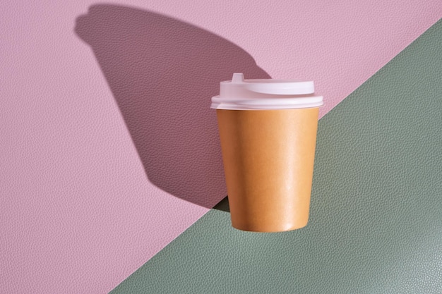 Einwegbecher aus Papier für heißen Kaffee und Tee auf rosa-grünem Hintergrund. Konzept und Trend von Speisen zum Mitnehmen.