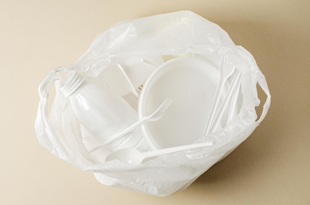 Einweggeschirr in einer weißen Plastiktüte Das Konzept der Verschmutzung der Natur