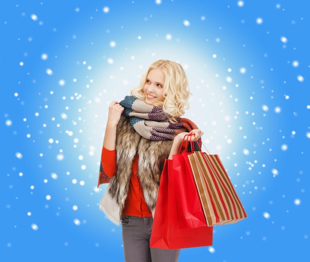 Einzelhandels- und Verkaufskonzept - glückliches Teenager-Mädchen in Winterkleidung mit Einkaufstüten