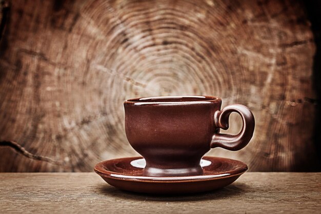 Einzelne braune Kaffeetasse auf Vintage-Holzhintergrund mit Kreuzschnitt aus Baumstamm