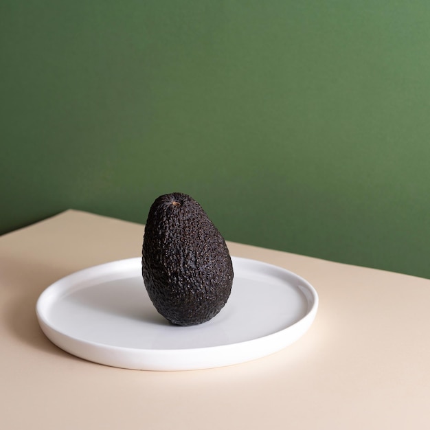 Einzelne frische Avocado präsentiert auf grünem Hintergrund kreatives Minimalismus-Konzept mit Kopierraum