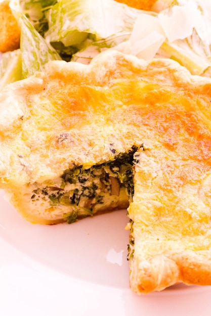 Einzelne Spinatquiche mit Salat serviert.