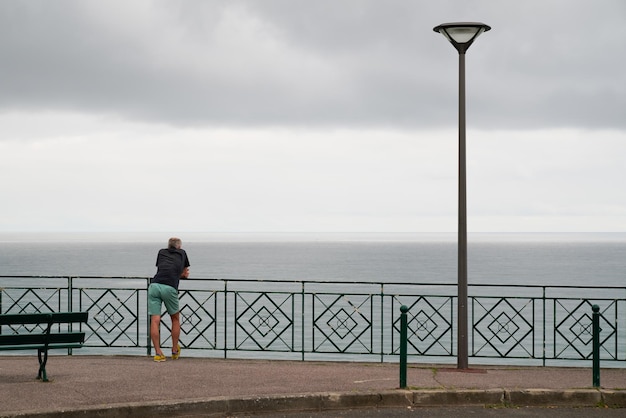 Einzelner Mann Rückansicht auf Zaun vor dem Atlantischen Ozean in der Stadt Biarritz Baskenland Frankreich