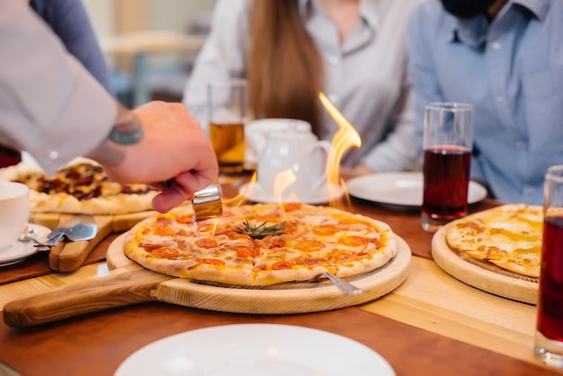 Einzigartige heiße Pizza in Brandnahaufnahme während eines freundlichen Abendessens