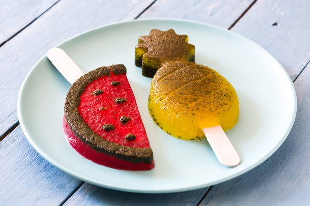 Eis am Stiel Ananas und Wassermelone auf blauem Holztisch