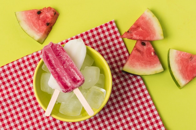 Foto eis am stiel in der schüssel nahe serviette und scheiben der frucht