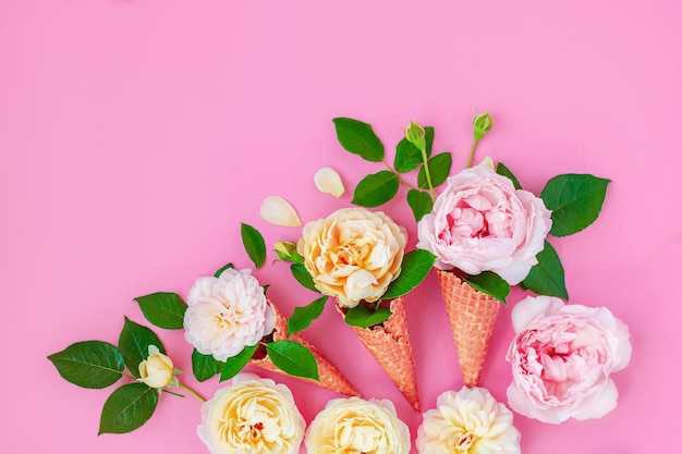 Eis aus Pfingstrosenblüten in einem Waffelkegel auf rosafarbenem Hintergrund von oben, schönes Blumenarrangement, Vintage-Farbe, flache Lage. Blumenrahmen mit leerem Platz für Text.