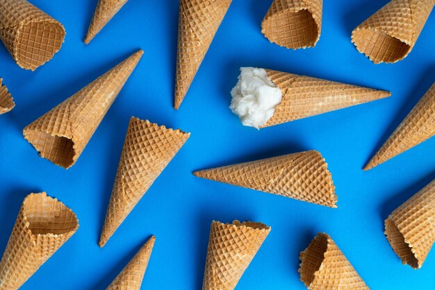 Eis und Waffel leere Eistüten auf blauem Hintergrund flach gelegt