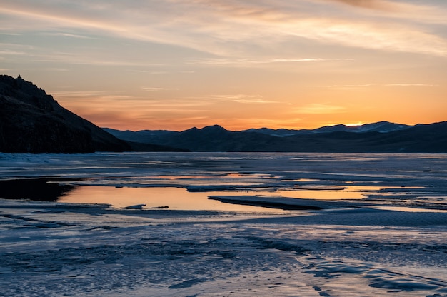 Eis und Wasser in der Nähe des Berges am zugefrorenen Baikalsee vor Sonnenaufgang