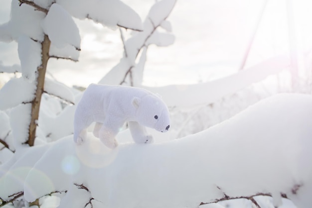 Eisbärspielzeugspaziergang auf schneebedecktem Ast des Busches